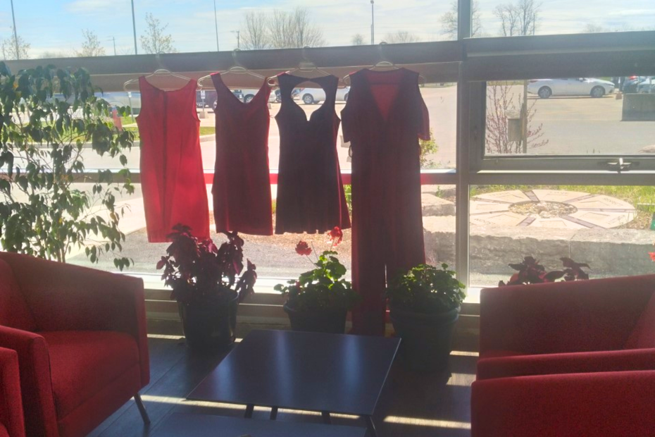 Four red dresses are hung in the window of the Indigenous Centre